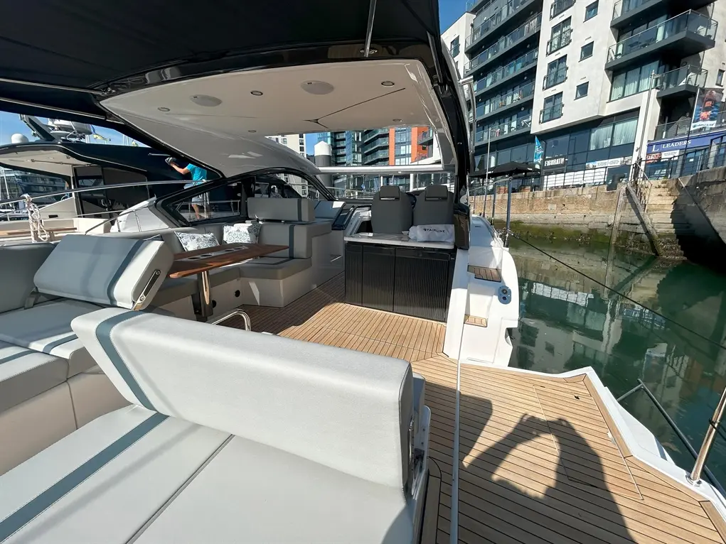 Luxury yacht interior with modern seating, a wooden deck, and a waterfront view; a person is seen in the background adjusting equipment.